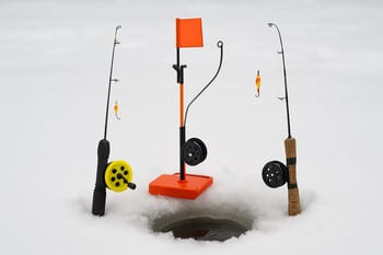 Несколько зимних удочек с разными катушками на снегу