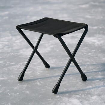 Складной стул стоит рядом с лункой на зимнем льду