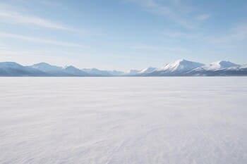 Следы саней и рыболова на широком заснеженном плато водоёма